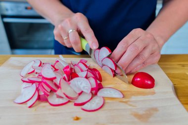 Ahşap masada turpları dilimleyen kadın. Kendi bahçemden taze sebzeler.