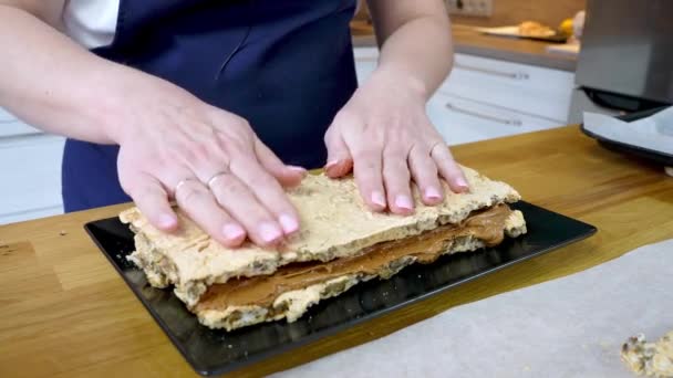 Kucharz kładzie drugą warstwę tortu beżowego. Proces wytwarzania czekolady z orzechami i śmietaną. — Wideo stockowe