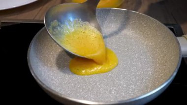 Omlet hazırlama işlemi. Bir kadın tavaya yumurta döküyor..