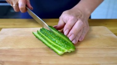 Kadın eli salatalığı keser. Tahta kesme tahtasında taze sebze dilimliyorum..