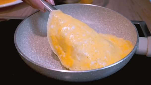 Omelete making process. Woman flips the half ready aggs to the other side. — Stock Video