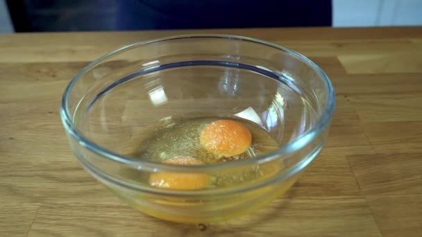 Жіночі руки додають сіль, перець і оливкову олію в миску з тріщинами. І батоги з виделкою. процес приготування яєць . — стокове відео