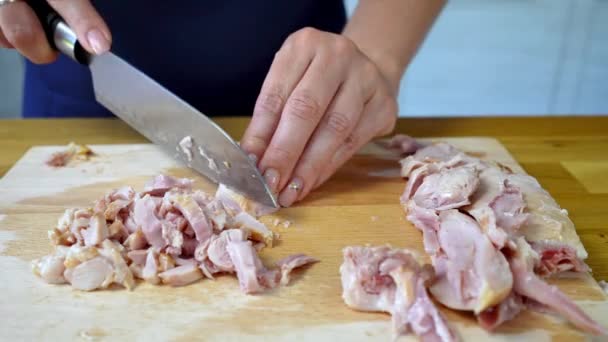 Le mani femminili con un coltello tagliano un petto di pollo affumicato su un'asse di cucina di legno. processo di cottura di una deliziosa insalata. — Video Stock