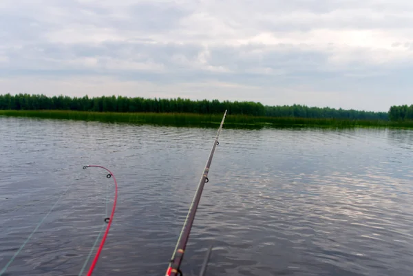 Un pescador en un barco inflable atrapa peces en el spinning. El proceso de curricán en el lago —  Fotos de Stock