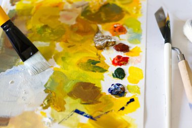 Ressam resim yapmak için farklı renkleri boya fırçasıyla karıştırır..