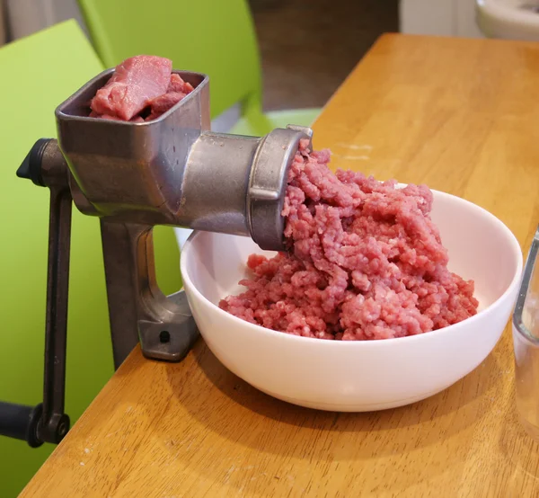 Fresh meat with onions become meat grinder. — Stock Photo, Image