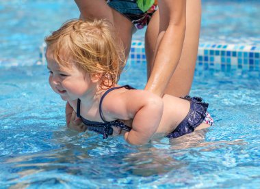 Kız bebek annesiyle havuzunda yüzmeyi öğrenmek