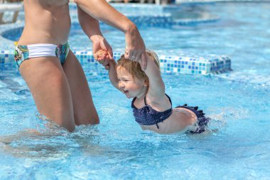 Kız bebek annesiyle havuzunda yüzmeyi öğrenmek