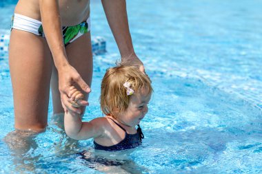 Kız bebek annesiyle havuzunda yüzmeyi öğrenmek