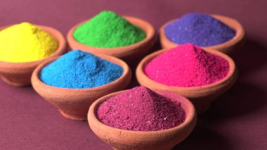 Diwali Festivali kaselerde rengarenk rangoli, arka planda kil lamba veya diya gösteriyor.