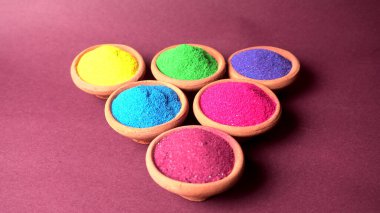 Diwali Festivali kaselerde rengarenk rangoli, arka planda kil lamba veya diya gösteriyor.