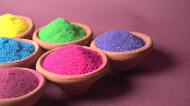 Diwali Festivali kaselerde rengarenk rangoli, arka planda kil lamba veya diya gösteriyor.