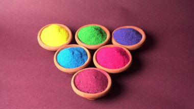 Diwali Festivali kaselerde rengarenk rangoli, arka planda kil lamba veya diya gösteriyor.