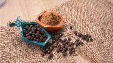 View of spices in the color bowls on wooden table with sackcloth, allspice 