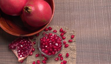 View of ripe pomegranates  and pomegranate seeds on the table with sackcloth clipart