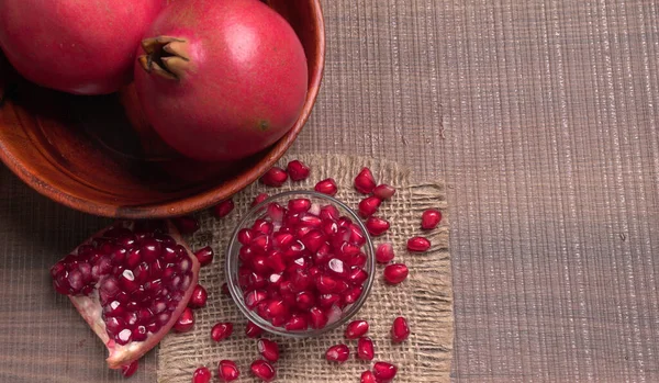 View of ripe pomegranates  and pomegranate seeds on the table with sackcloth