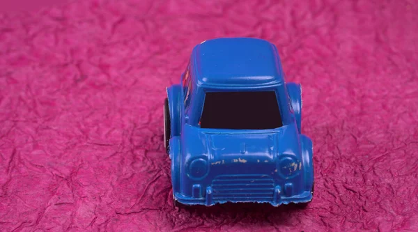 blue plastic toy car on pink background