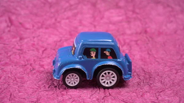 blue plastic toy car on pink background