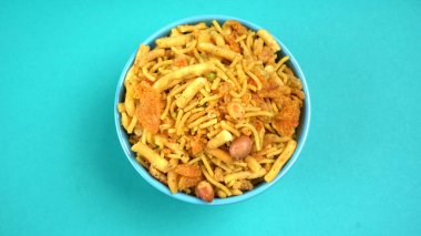 Mavi arka planda karışık gevrek atıştırmalıkları olan kasenin üst görüntüsü