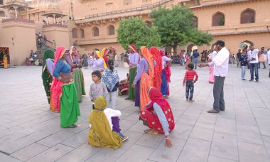 JAIPUR, INDIA 11 AĞUSTOS 2019: Geleneksel elbiseli kimliği belirsiz turist kadın ziyaretçiler grubu. Amber Fort avlusunda dans etmek ve eğlenmek Hindistan 'ın en önemli turistik yerlerinden biridir.