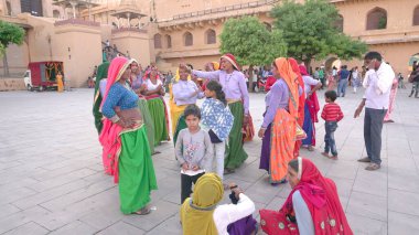 JAIPUR, INDIA 11 AĞUSTOS 2019: Geleneksel elbiseli kimliği belirsiz turist kadın ziyaretçiler grubu. Amber Fort avlusunda dans etmek ve eğlenmek Hindistan 'ın en önemli turistik yerlerinden biridir.