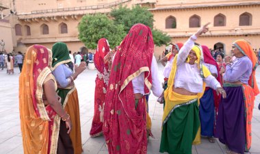 JAIPUR, INDIA 11 AĞUSTOS 2019: Geleneksel elbiseli kimliği belirsiz turist kadın ziyaretçiler grubu. Amber Fort avlusunda dans etmek ve eğlenmek Hindistan 'ın en önemli turistik yerlerinden biridir.