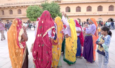 JAIPUR, INDIA 11 AĞUSTOS 2019: Geleneksel elbiseli kimliği belirsiz turist kadın ziyaretçiler grubu. Amber Fort avlusunda dans etmek ve eğlenmek Hindistan 'ın en önemli turistik yerlerinden biridir.