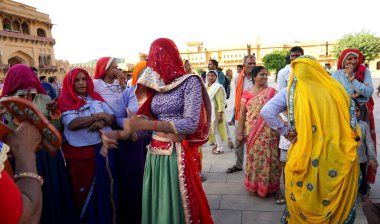 JAIPUR, INDIA 11 AĞUSTOS 2019: Geleneksel elbiseli kimliği belirsiz turist kadın ziyaretçiler grubu. Amber Fort avlusunda dans etmek ve eğlenmek Hindistan 'ın en önemli turistik yerlerinden biridir.