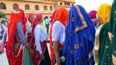 JAIPUR, INDIA 11 AĞUSTOS 2019: Geleneksel elbiseli kimliği belirsiz turist kadın ziyaretçiler grubu. Amber Fort avlusunda dans etmek ve eğlenmek Hindistan 'ın en önemli turistik yerlerinden biridir.