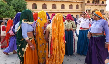 JAIPUR, INDIA 11 AĞUSTOS 2019: Geleneksel elbiseli kimliği belirsiz turist kadın ziyaretçiler grubu. Amber Fort avlusunda dans etmek ve eğlenmek Hindistan 'ın en önemli turistik yerlerinden biridir.