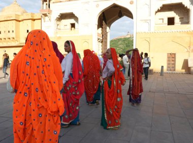 JAIPUR, INDIA 11 AĞUSTOS 2019: Geleneksel elbiseli kimliği belirsiz turist kadın ziyaretçiler grubu. Amber Fort avlusunda dans etmek ve eğlenmek Hindistan 'ın en önemli turistik yerlerinden biridir.