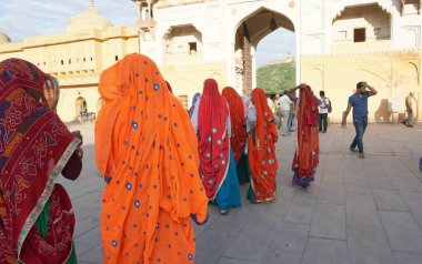 JAIPUR, INDIA 11 AĞUSTOS 2019: Geleneksel elbiseli kimliği belirsiz turist kadın ziyaretçiler grubu. Amber Fort avlusunda dans etmek ve eğlenmek Hindistan 'ın en önemli turistik yerlerinden biridir.