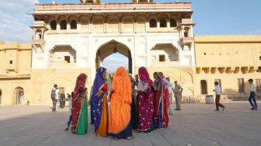 JAIPUR, INDIA 11 AĞUSTOS 2019: Geleneksel elbiseli kimliği belirsiz turist kadın ziyaretçiler grubu. Amber Fort avlusunda dans etmek ve eğlenmek Hindistan 'ın en önemli turistik yerlerinden biridir.
