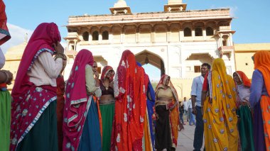 JAIPUR, INDIA 11 AĞUSTOS 2019: Geleneksel elbiseli kimliği belirsiz turist kadın ziyaretçiler grubu. Amber Fort avlusunda dans etmek ve eğlenmek Hindistan 'ın en önemli turistik yerlerinden biridir.