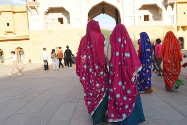 JAIPUR, INDIA 11 AĞUSTOS 2019: Geleneksel elbiseli kimliği belirsiz turist kadın ziyaretçiler grubu. Amber Fort avlusunda dans etmek ve eğlenmek Hindistan 'ın en önemli turistik yerlerinden biridir.