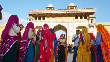 JAIPUR, INDIA 11 AĞUSTOS 2019: Geleneksel elbiseli kimliği belirsiz turist kadın ziyaretçiler grubu. Amber Fort avlusunda dans etmek ve eğlenmek Hindistan 'ın en önemli turistik yerlerinden biridir.