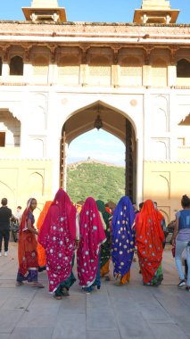 JAIPUR, INDIA 11 AĞUSTOS 2019: Geleneksel elbiseli kimliği belirsiz turist kadın ziyaretçiler grubu. Amber Fort avlusunda dans etmek ve eğlenmek Hindistan 'ın en önemli turistik yerlerinden biridir.