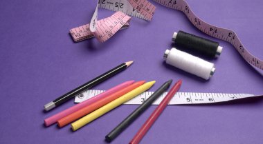 Cetvel, boya kalemleri ve iplikler masanın üzerinde.