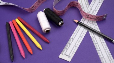 Cetvel, boya kalemleri ve iplikler masanın üzerinde.