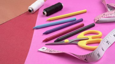 Cetvel, boya kalemleri ve iplikler masanın üzerinde.