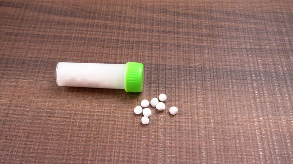 Haplardan oluşan homeopatik ilaçların ve içinde sıvı homeopatik madde bulunan bir şişenin yakın plan görüntüsü..