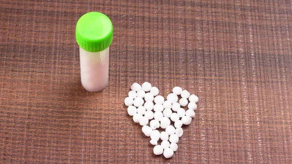 Closeup image of homeopathic medicine consisting of the pills and a bottle containing a liquid homeopathic substance.