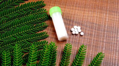 Haplardan oluşan homeopatik ilaçların ve içinde sıvı homeopatik madde bulunan bir şişenin yakın plan görüntüsü..