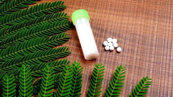 Closeup image of homeopathic medicine consisting of the pills and a bottle containing a liquid homeopathic substance.