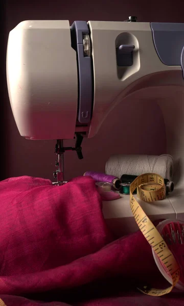 Modern sewing machine with thread and fabric on table