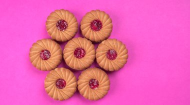 Pembe arka planda reçelli bisküvilerin üst görüntüsü. Sandviç bisküvileri veya kremalı bisküviler izole edilmiş..
