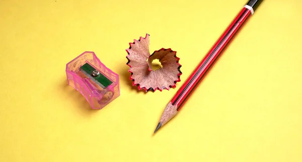 Sarı arkaplanda izole edilmiş kalem ve kalem açacağı..