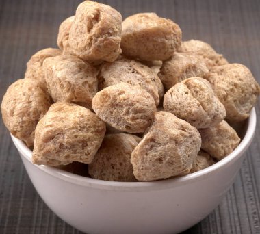 Koyu arkaplanda çiğ soya parçaları var. Sağlıklı, besleyici soya eti, beyaz kasede parçalar. Vejetaryen gıda konsepti.