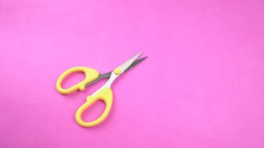 Pembe arka planda sarı makasın üst görüntüsü. Kağıt ve ince malzemeler kesmek için makas kullanılır.