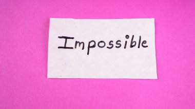 Kendini motive etme konsepti. Beyaz kağıda pembe arkaplan üzerine imkansız sözcük yaz